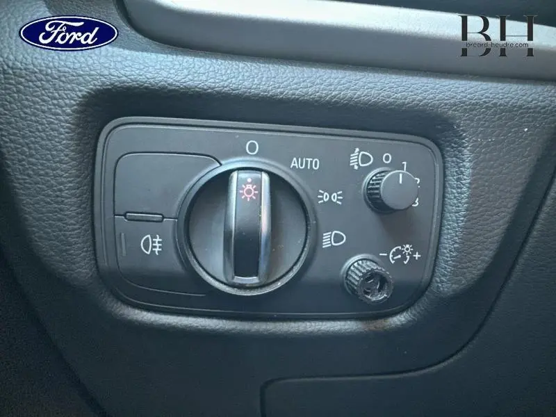 Panneau de commande des phares avec molette et réglages lumineux sur tableau de bord noir d'une Audi A3 Sportback noire.