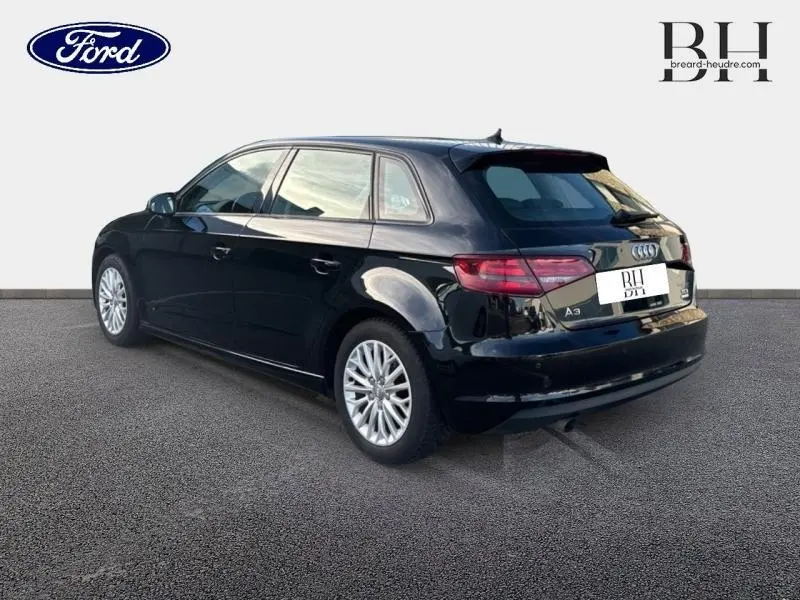 Audi A3 Sportback noir brillant vue 3/4 arrière droit, soulignant son becquet et jantes alu élégantes.