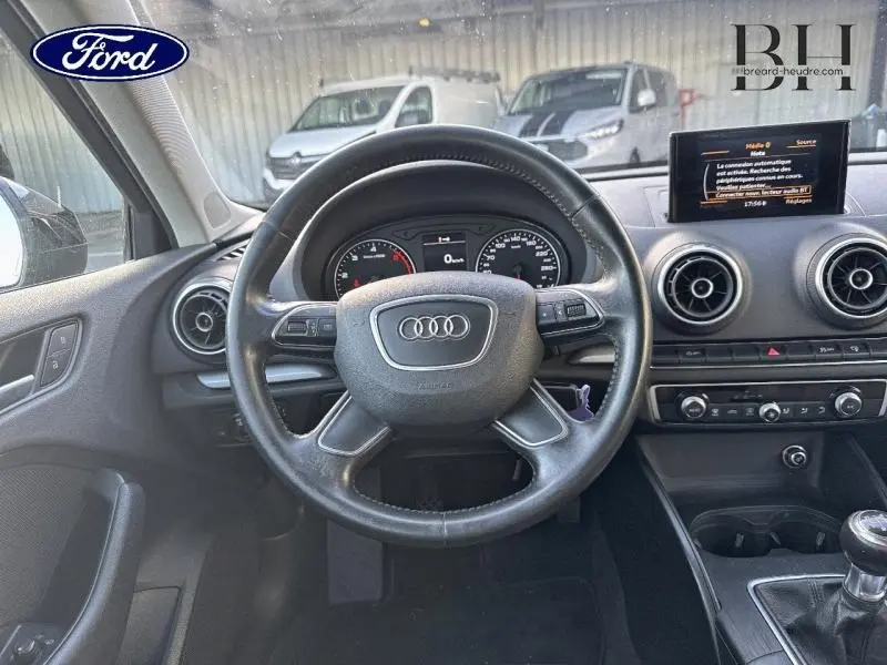 Vue intérieure du volant cuir multifonction d'une Audi A3 Sportback 1.6 TDI noire, avec tableau de bord et écran central visibles.