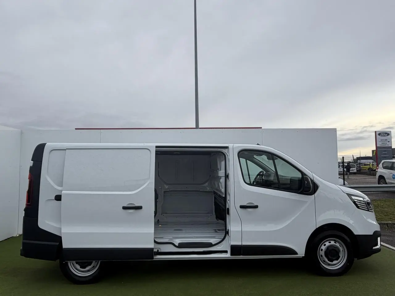Vue latérale droite d’un Renault Trafic Fourgon blanc Glacier avec porte coulissante ouverte montrant l’espace de chargement vide.