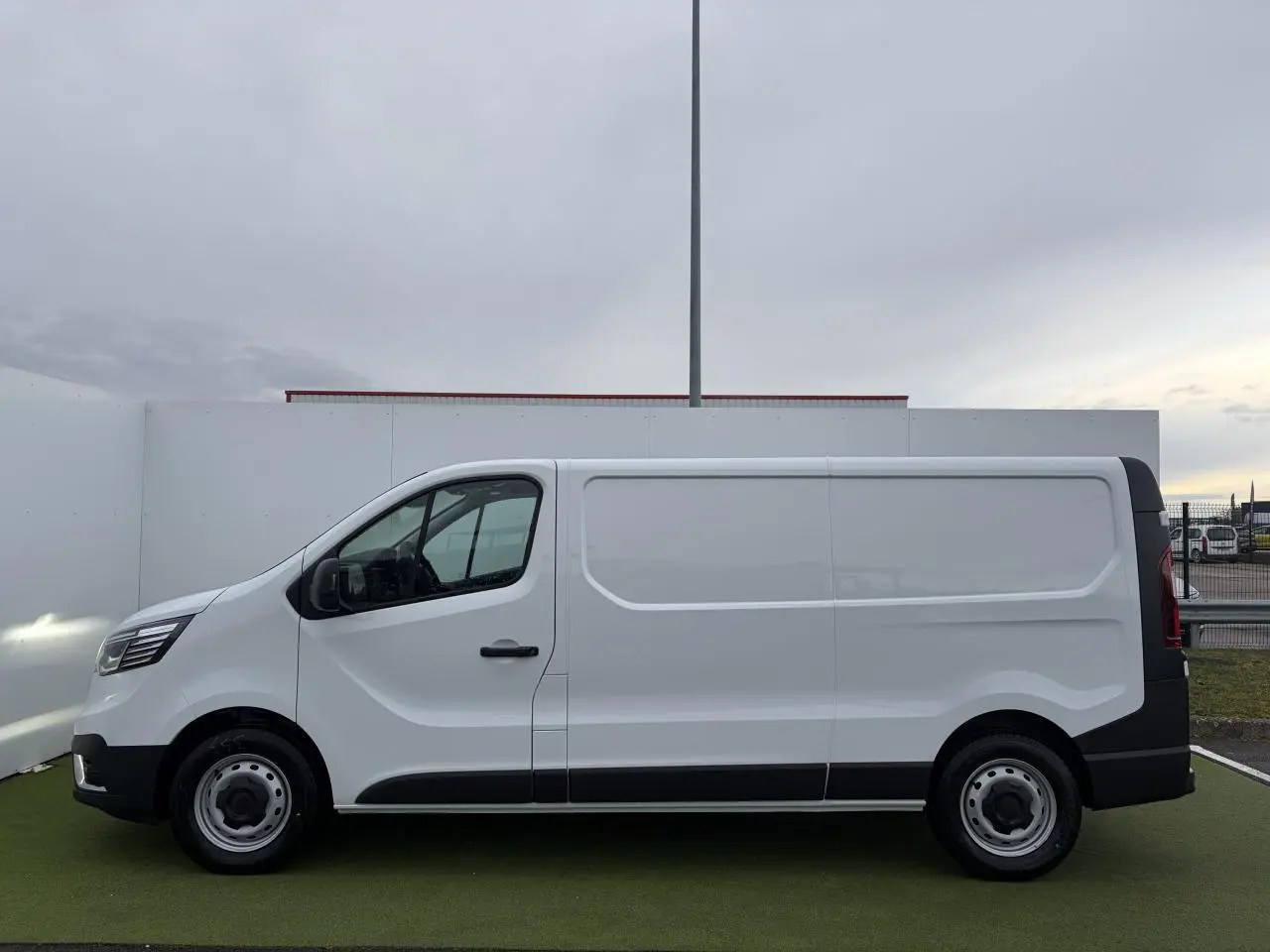 Profil droit d’un Renault Trafic Fourgon blanc glacier 2025 avec jantes tôles 16 pouces et porte latérale coulissante.