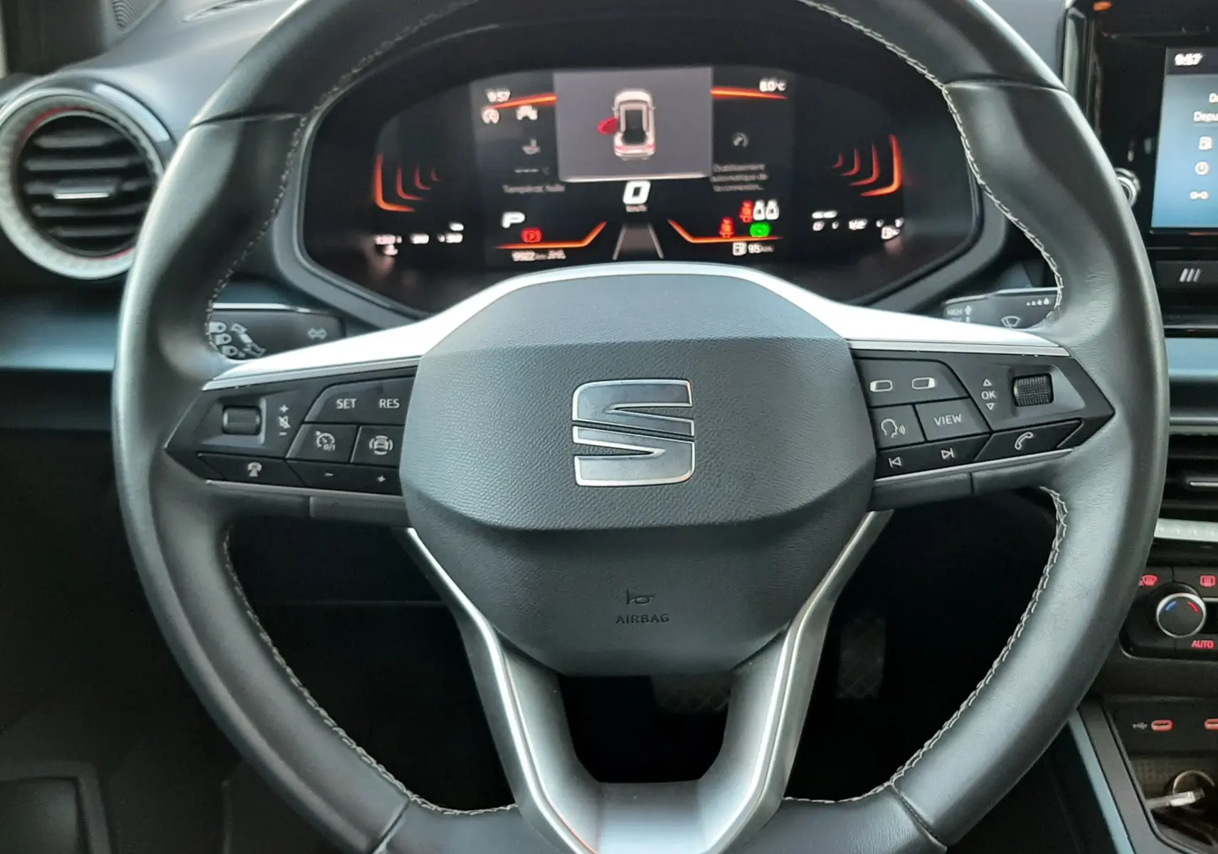 Vue rapprochée du volant noir de la SEAT Arona 2025 avec tableau de bord digital et commandes intégrées.