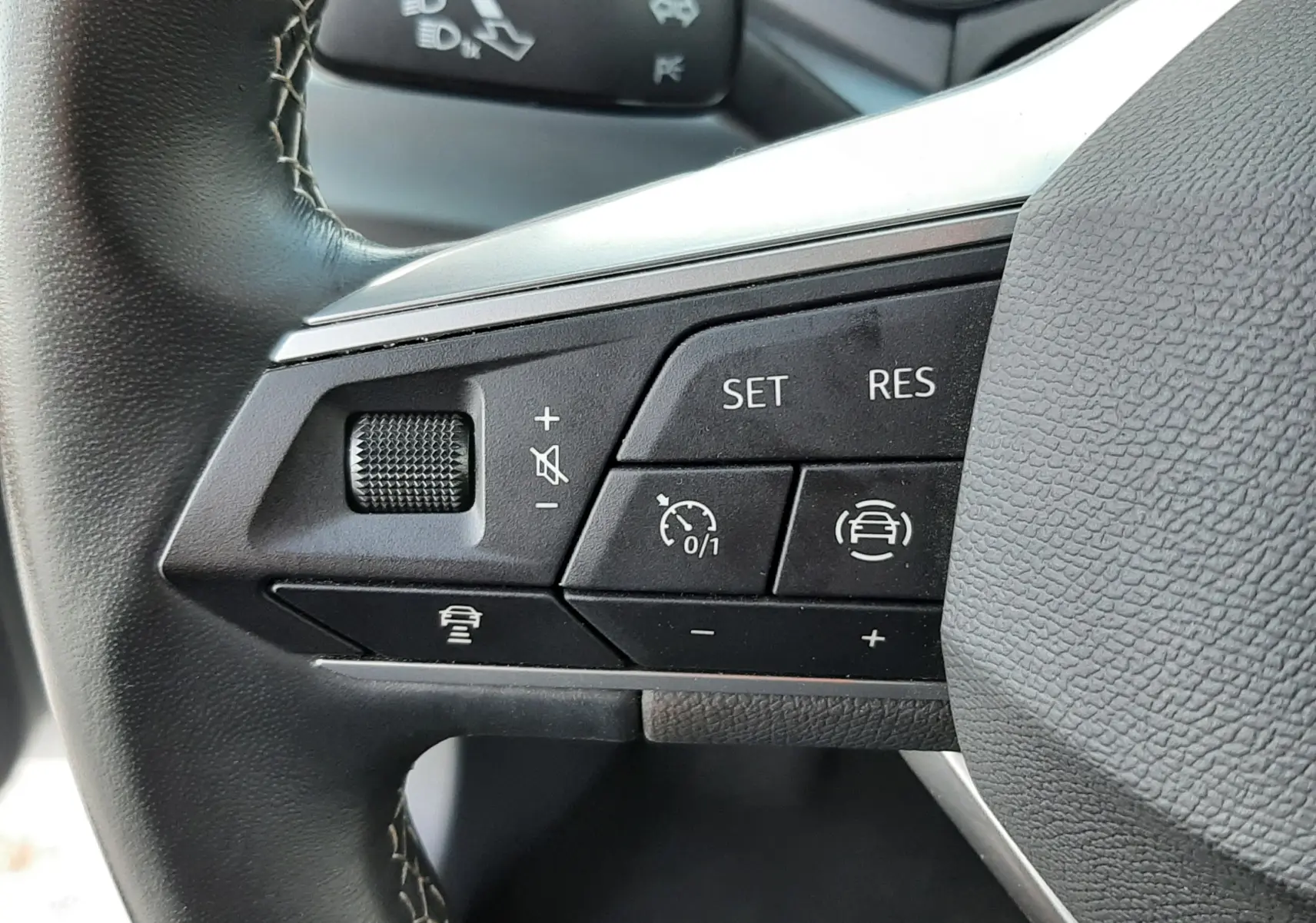 Gros plan sur les commandes au volant gauche du SEAT Arona 2025, finition X-PERIENCE, avec boutons de régulateur de vitesse et assistance.