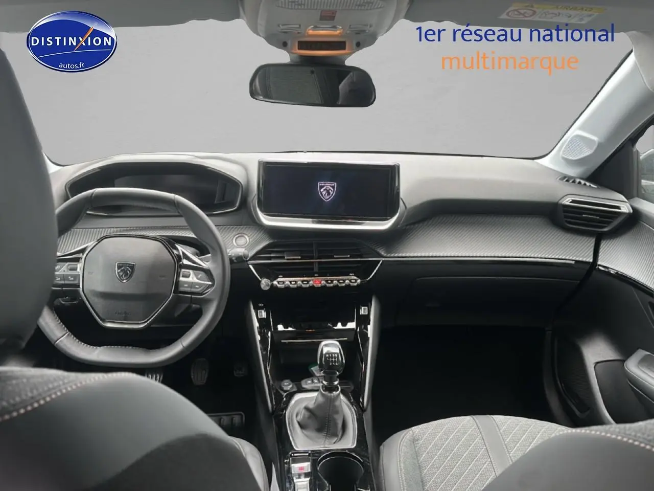 Vue intérieure avant de la Peugeot 208 1.2 PureTech 100 Allure 2024, tableau de bord gris avec écran tactile et boîte manuelle.
