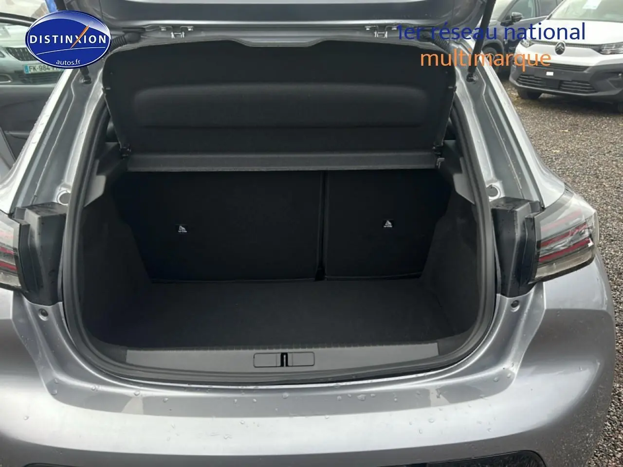 Coffre ouvert vu de l'arrière d'une Peugeot 208 1.2 PureTech 100 Allure gris Artense avec feux arrière LED visibles.