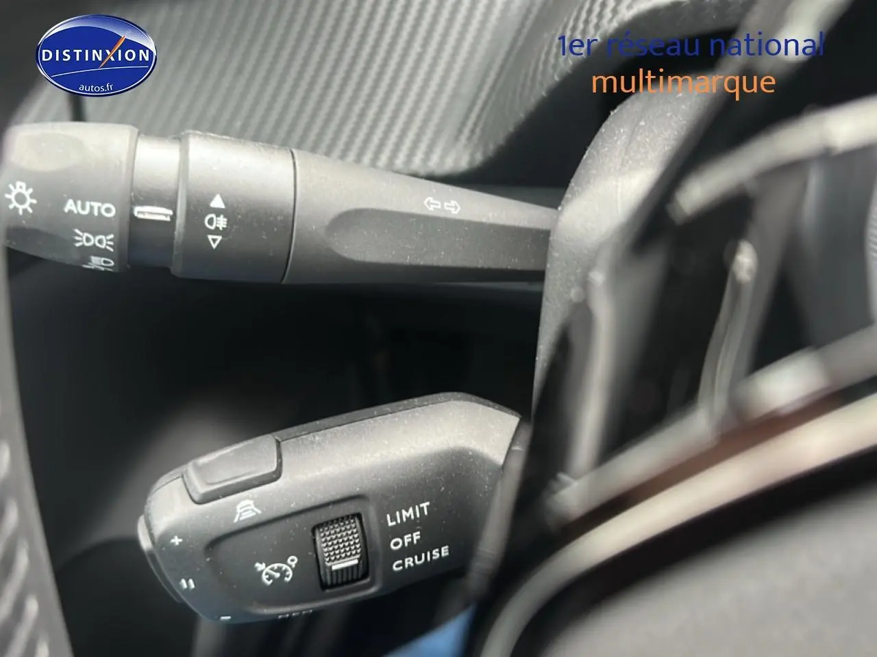 Gros plan sur les commandes du régulateur de vitesse et des phares dans l’habitacle d’une Peugeot 208 gris artense.