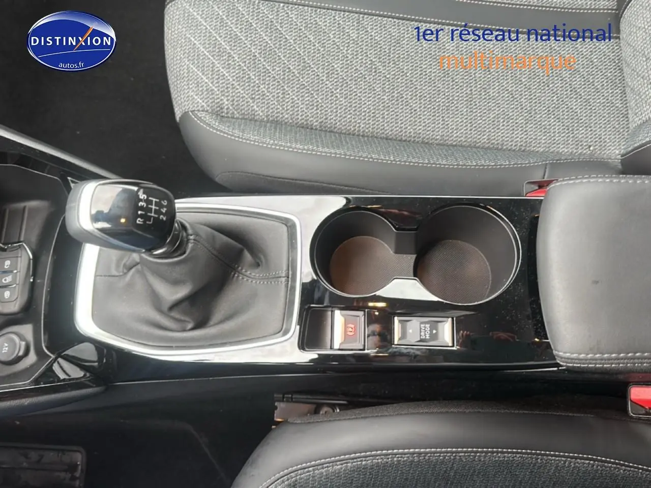 Vue plongeante sur la console centrale noire avec levier de vitesse manuel et accoudoir gris du Peugeot 208 gris Artense.