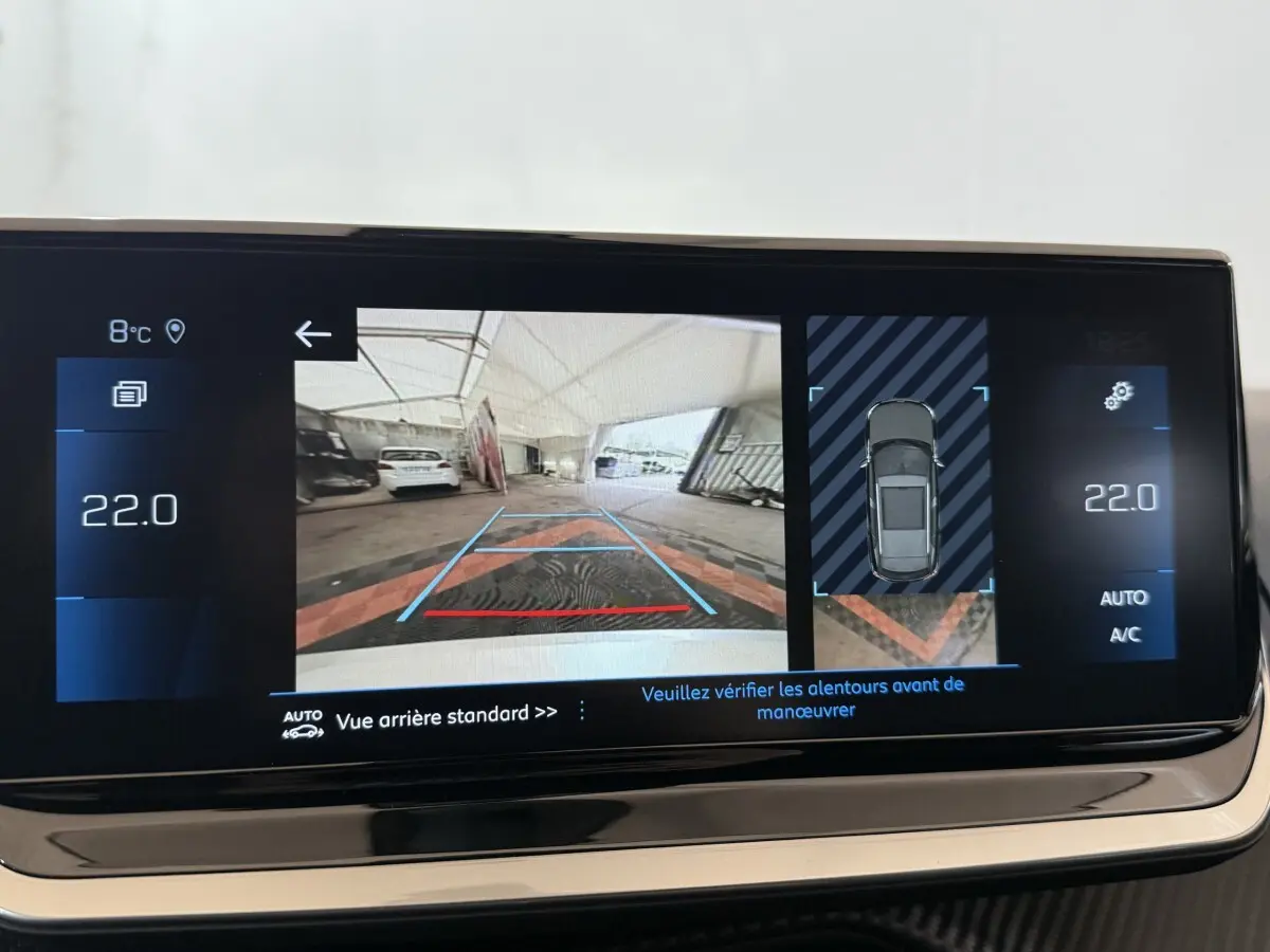 Écran tactile intérieur montrant la caméra de recul et l'aide au stationnement du Peugeot 2008 gris clair 2023.