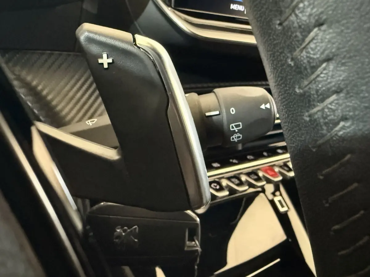 Gros plan sur la palette de changement de vitesse droite en plastique noir et chrome dans l’habitacle du Peugeot 2008 gris clair.