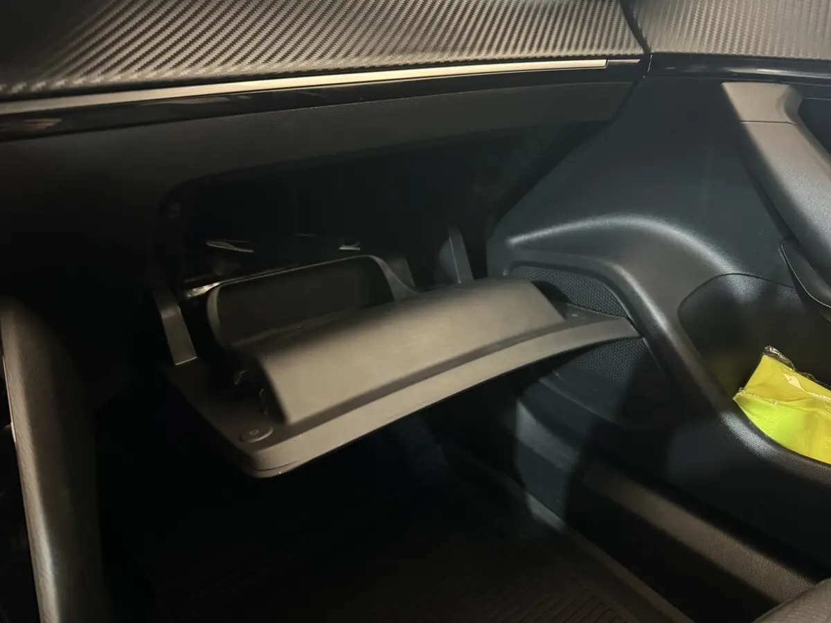 Vue intérieure côté passager du Peugeot 2008 gris clair 2023, montrant la boîte à gants ouverte et un rangement latéral.