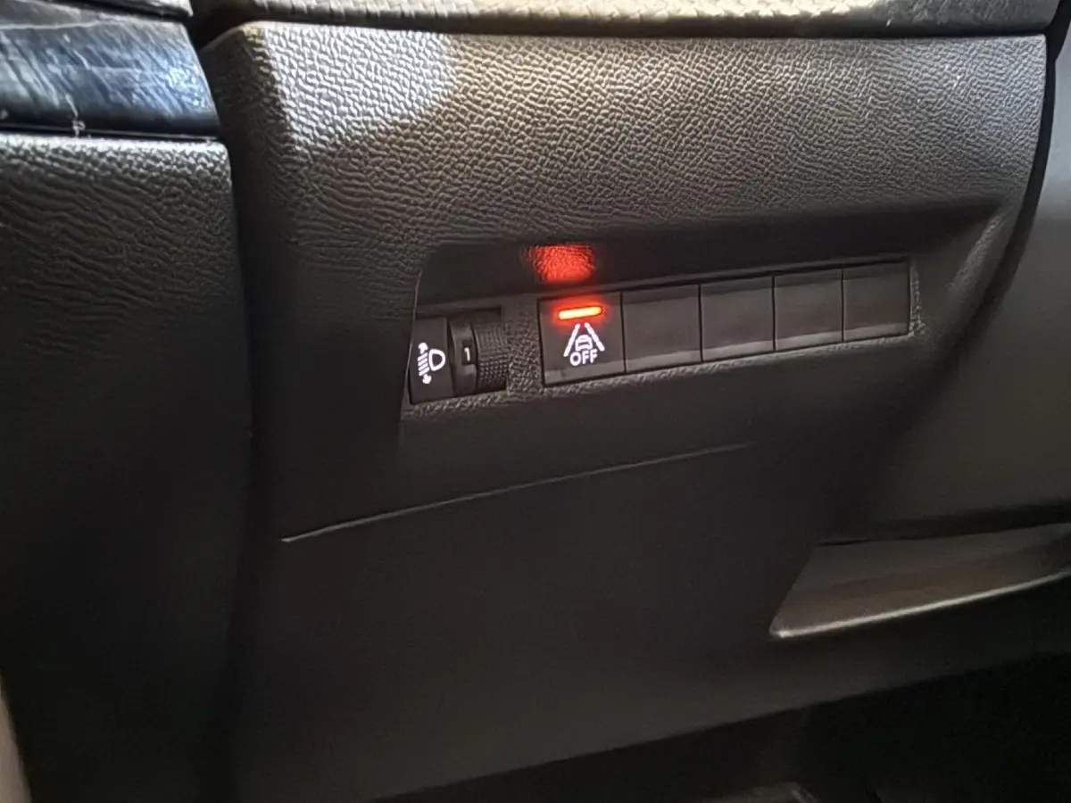 Gros plan sur les commandes noires du tableau de bord côté conducteur du Peugeot 2008 gris clair, voyant rouge allumé.