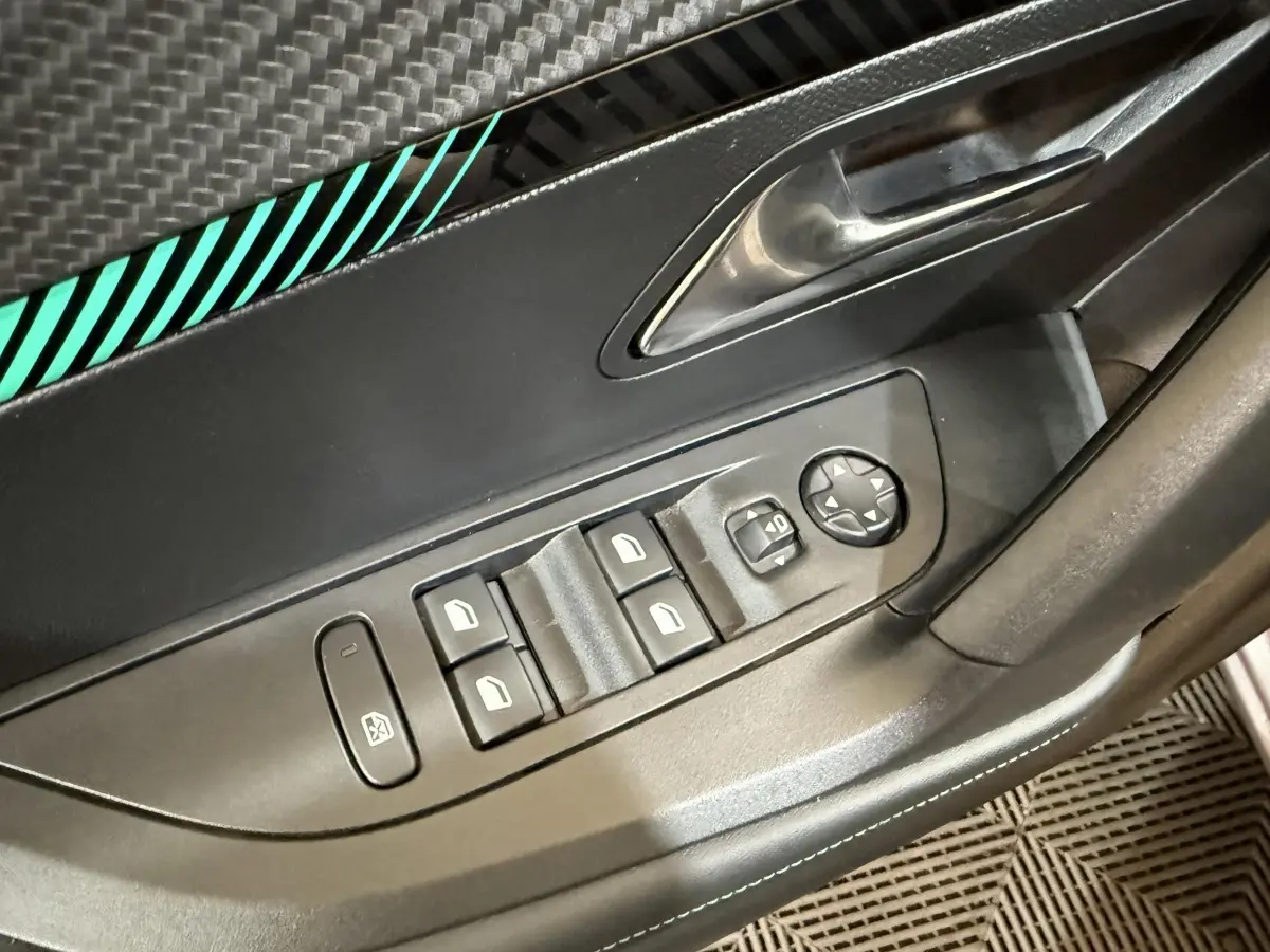 Gros plan sur la commande des vitres et rétroviseurs côté conducteur d’un Peugeot 2008 gris clair, intérieur noir.