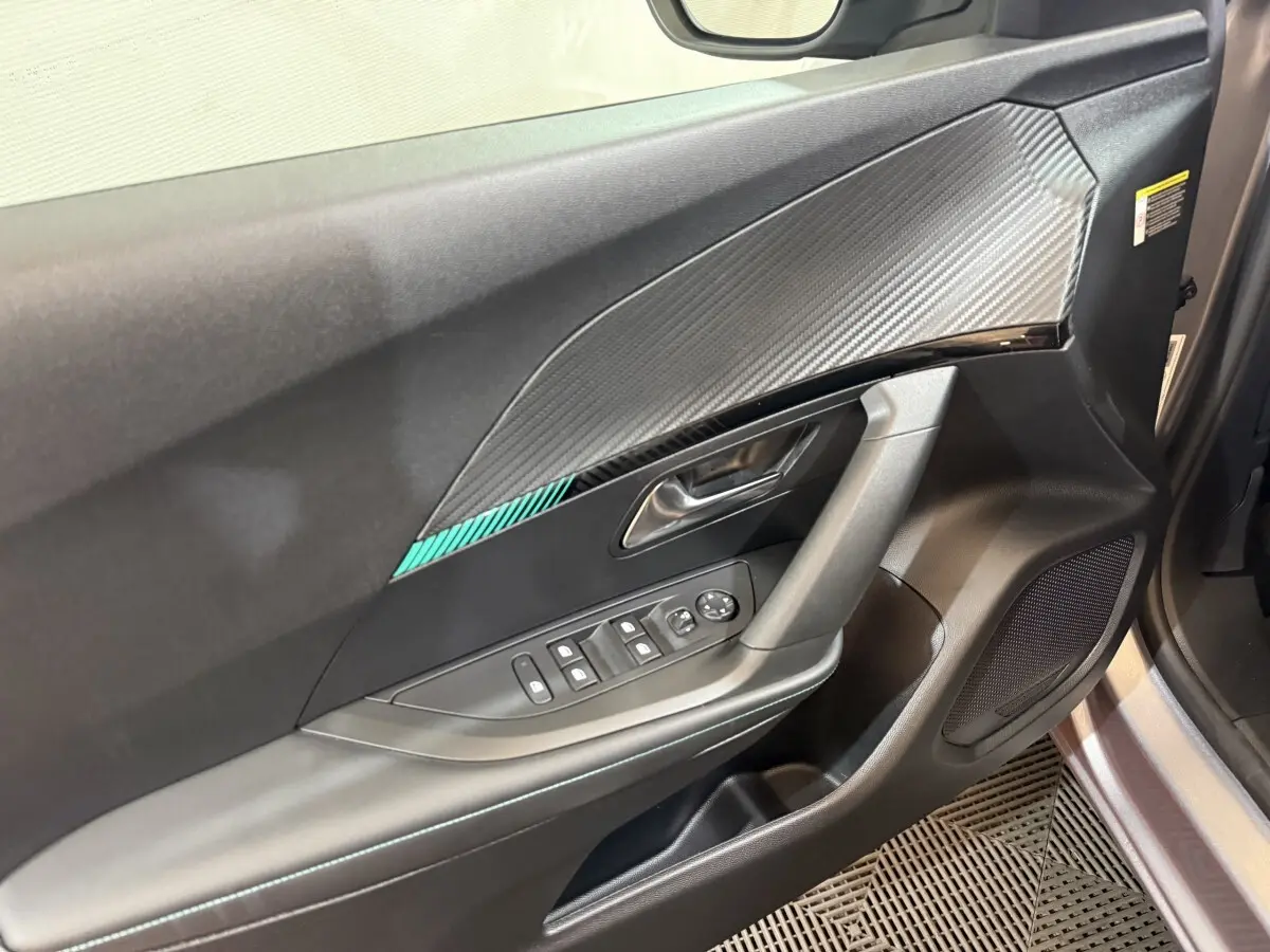 Vue rapprochée de la porte avant gauche du Peugeot 2008 gris clair, avec commandes électriques et insert décoratif.