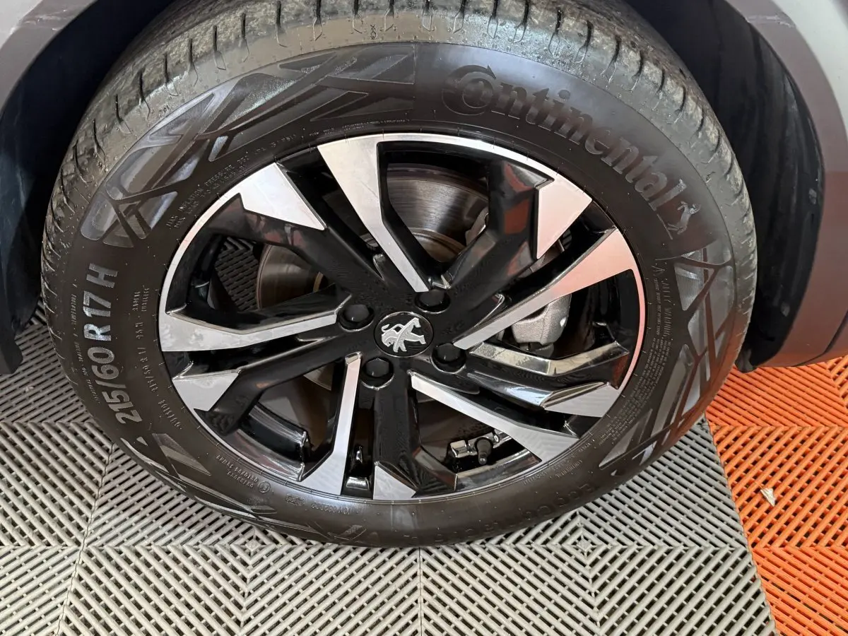 Gros plan sur la roue avant droite du Peugeot 2008 gris clair, jante alliage noire et argentée avec logo lion central.