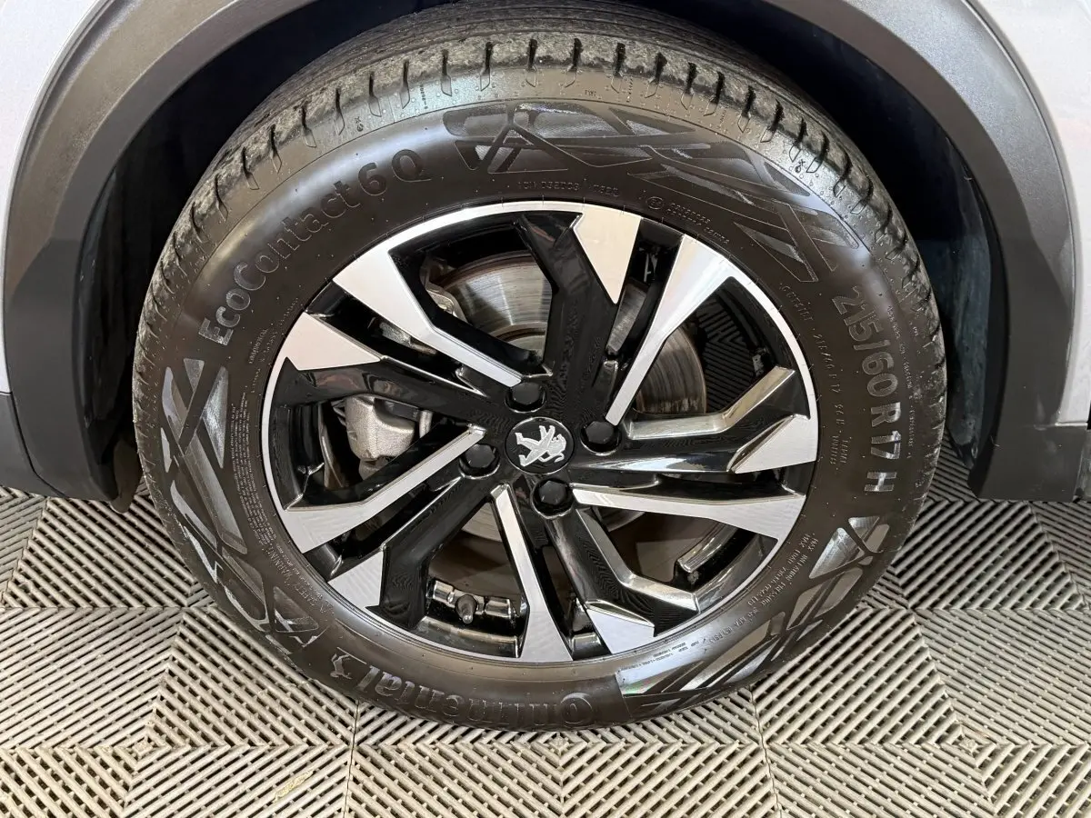 Gros plan sur la roue avant gauche du Peugeot 2008 gris clair avec jante alliage noire et argentée.