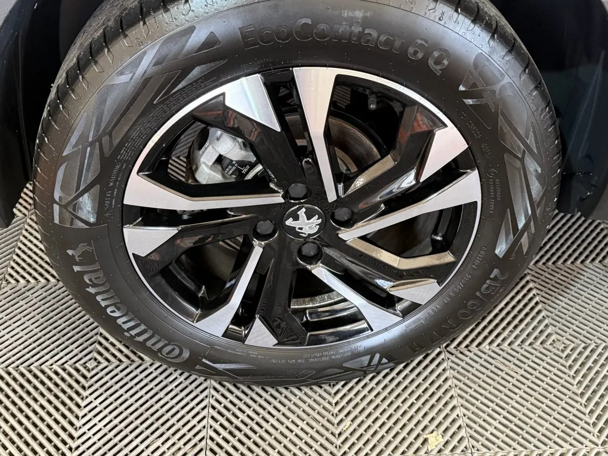 Gros plan sur la roue avant droite de la Peugeot 2008 gris clair, avec jante alliage bicolore et logo Peugeot central.