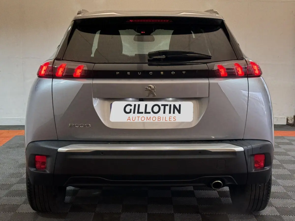 Vue arrière d'un Peugeot 2008 gris clair 2023 avec feux LED et logo lion centré sur le hayon.