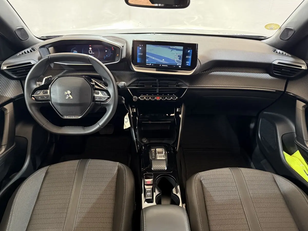 Vue intérieure avant du Peugeot 2008 gris clair 2023, tableau de bord moderne avec écran tactile central et volant compact.