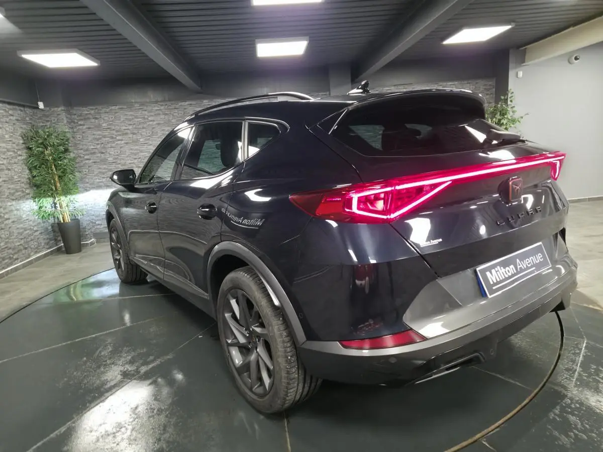Vue 3/4 arrière droite d'un CUPRA Formentor bleu avec feux arrière LED en bandeau lumineux et jantes alliage 18 pouces.