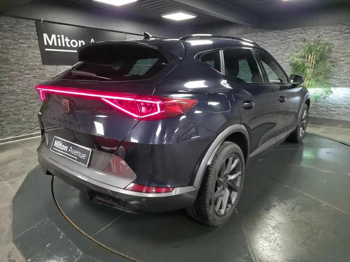 Vue 3/4 arrière droite du CUPRA Formentor bleu avec bandeau lumineux arrière LED et jantes alliage 18 pouces.