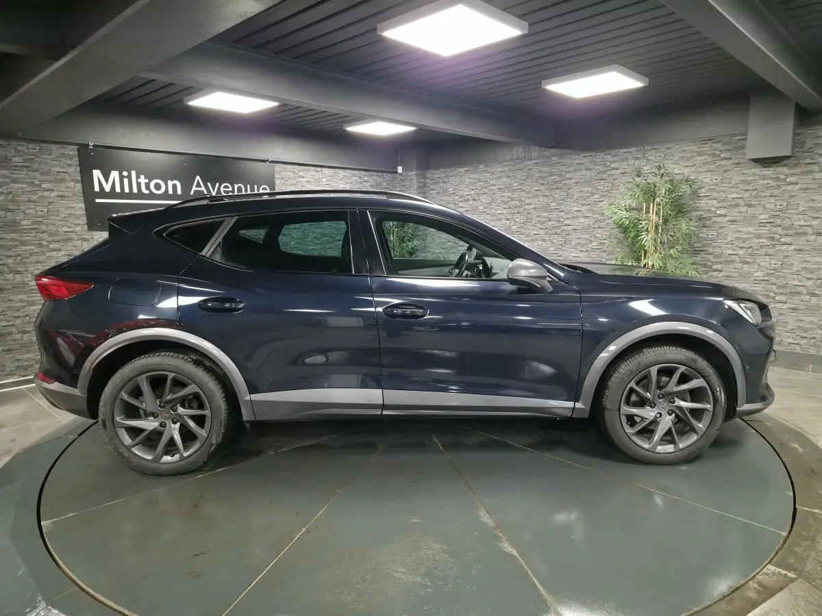 Vue de profil côté gauche d’un CUPRA Formentor bleu avec jantes alliage et détails de carrosserie contrastants gris.