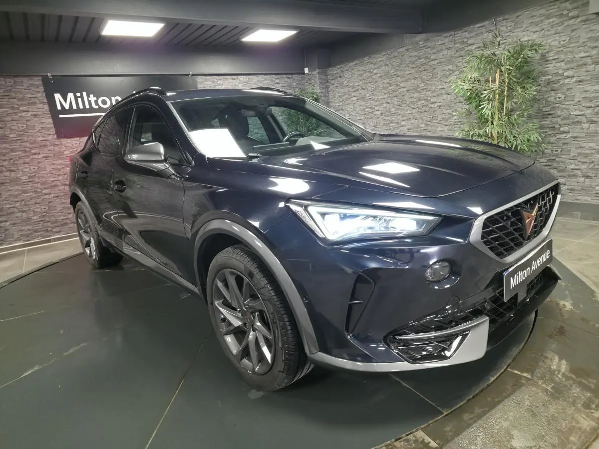 Vue 3/4 avant droit du CUPRA Formentor bleu avec calandre distinctive et jantes alliage 18 pouces en intérieur showroom.