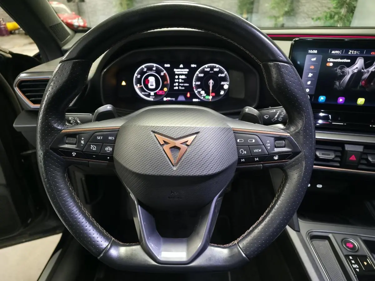 Vue rapprochée du volant sport en cuir perforé avec logo CUPRA cuivre et tableau de bord digital du Formentor 2022.