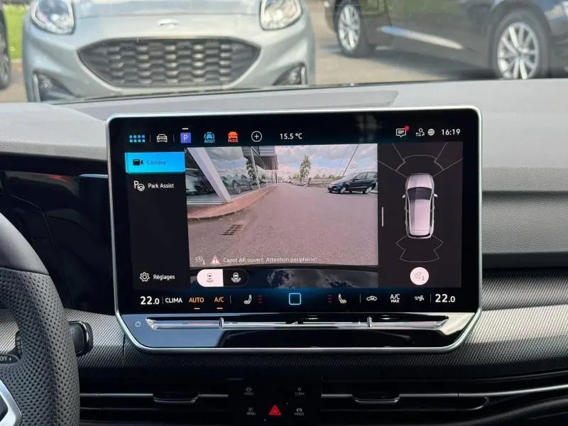 Vue intérieure de l'écran tactile affichant la caméra de recul et l'assistance au stationnement d'une Volkswagen Golf gris lunaire.