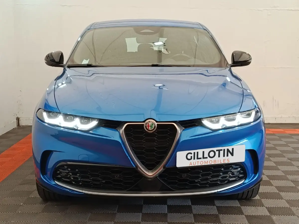 Vue frontale d'une Alfa Romeo Tonale 1.5T Hybrid 160 VGT bleu avec phares LED allumés et calandre caractéristique.