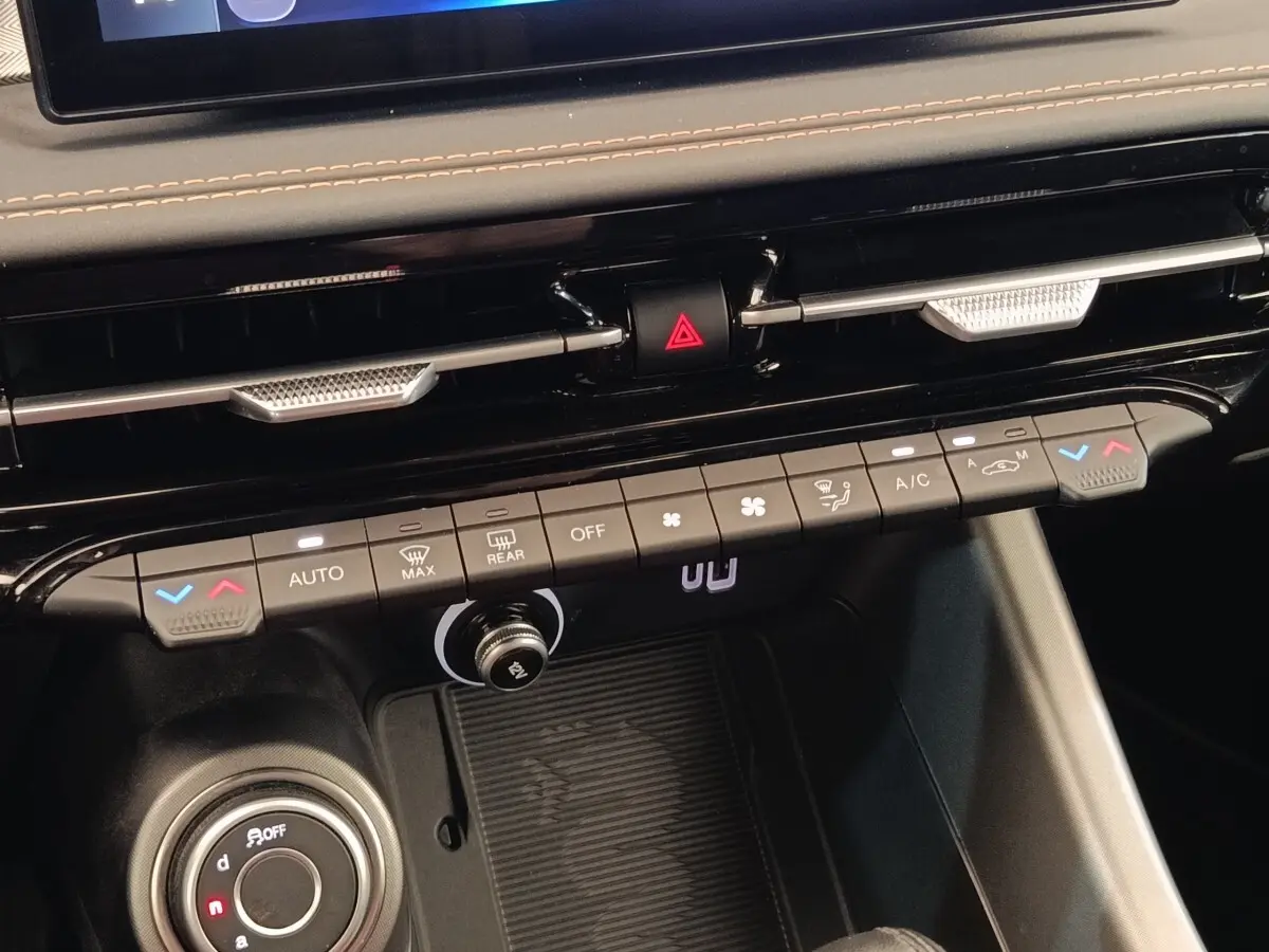 Vue rapprochée du tableau de bord central de l'Alfa Romeo Tonale 2023, montrant les commandes de climatisation et la roulette de sélection.