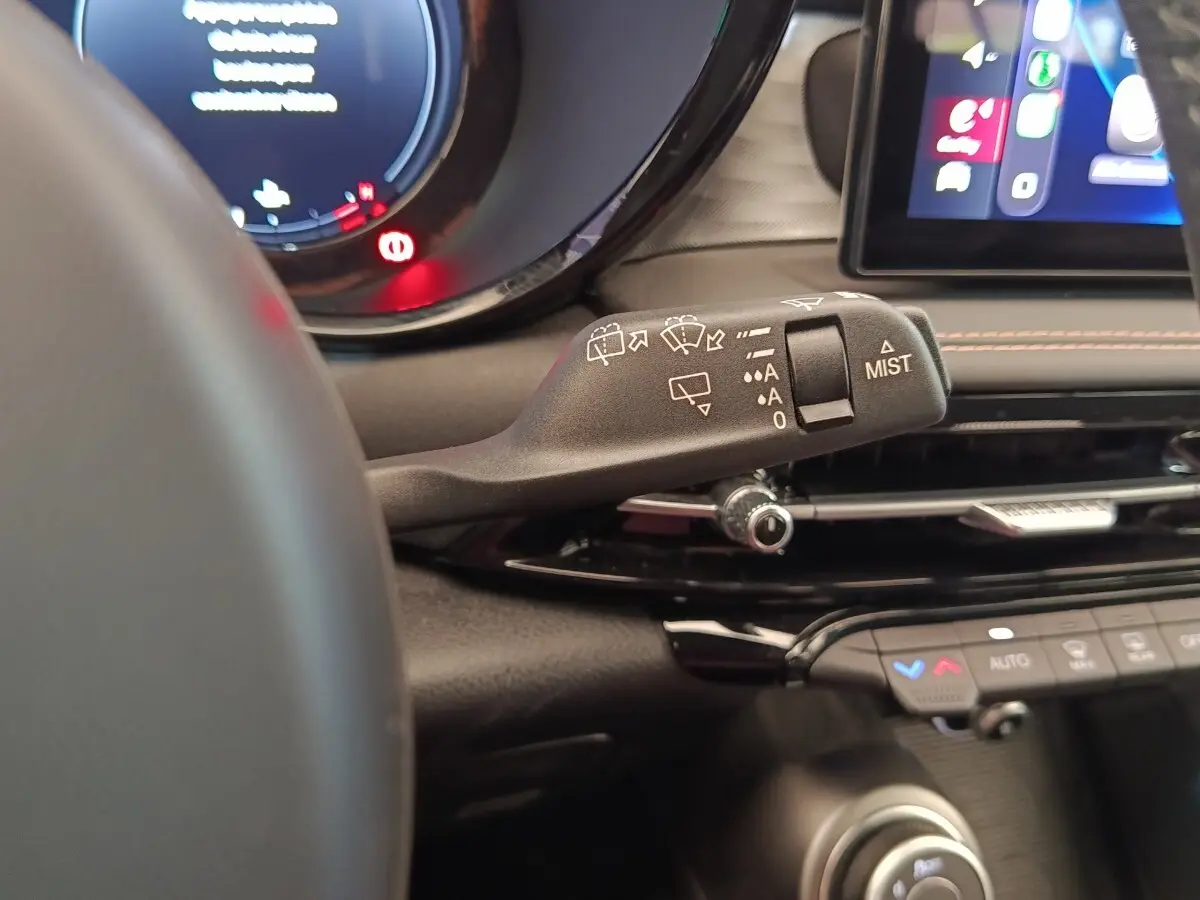 Gros plan sur la manette d’essuie-glace à gauche du volant dans l’habitacle de l’Alfa Romeo Tonale bleu 2023.