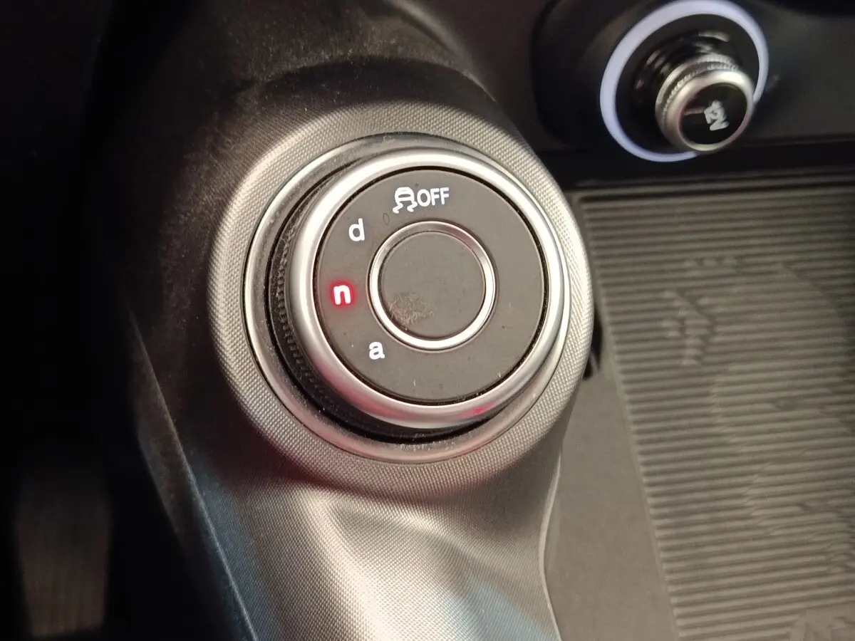 Gros plan sur la molette de sélection de mode de conduite de l'Alfa Romeo Tonale 1.5T Hybrid, intérieur noir.