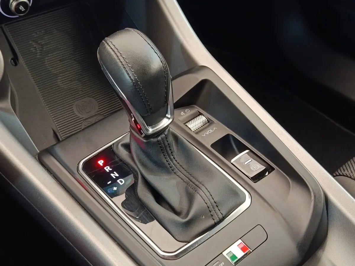 Gros plan sur le levier de vitesses automatique en cuir noir de l'Alfa Romeo Tonale 1.5T Hybrid 160 VGT, intérieur moderne.