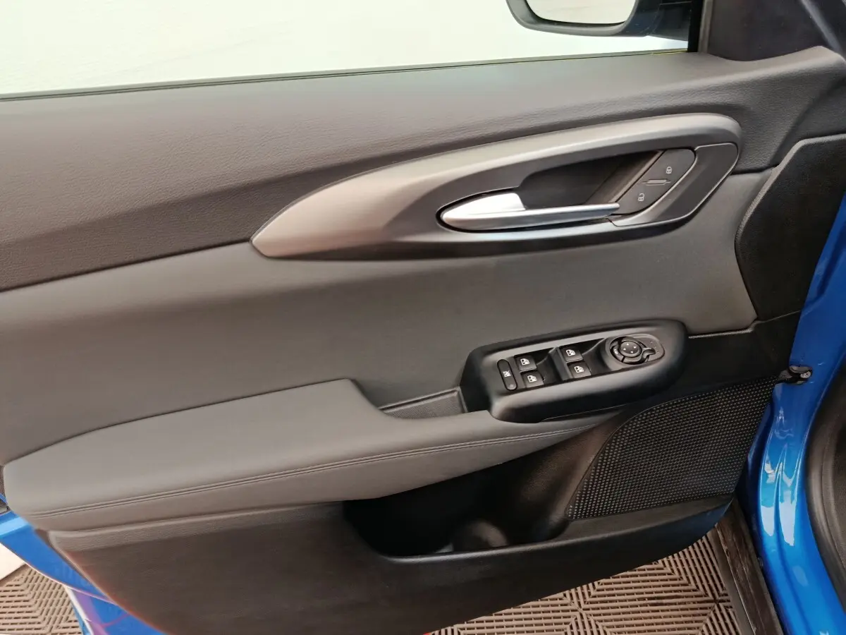 Vue rapprochée de la porte avant gauche bleu d’une Alfa Romeo Tonale 2023 avec commandes électriques et poignée argentée.