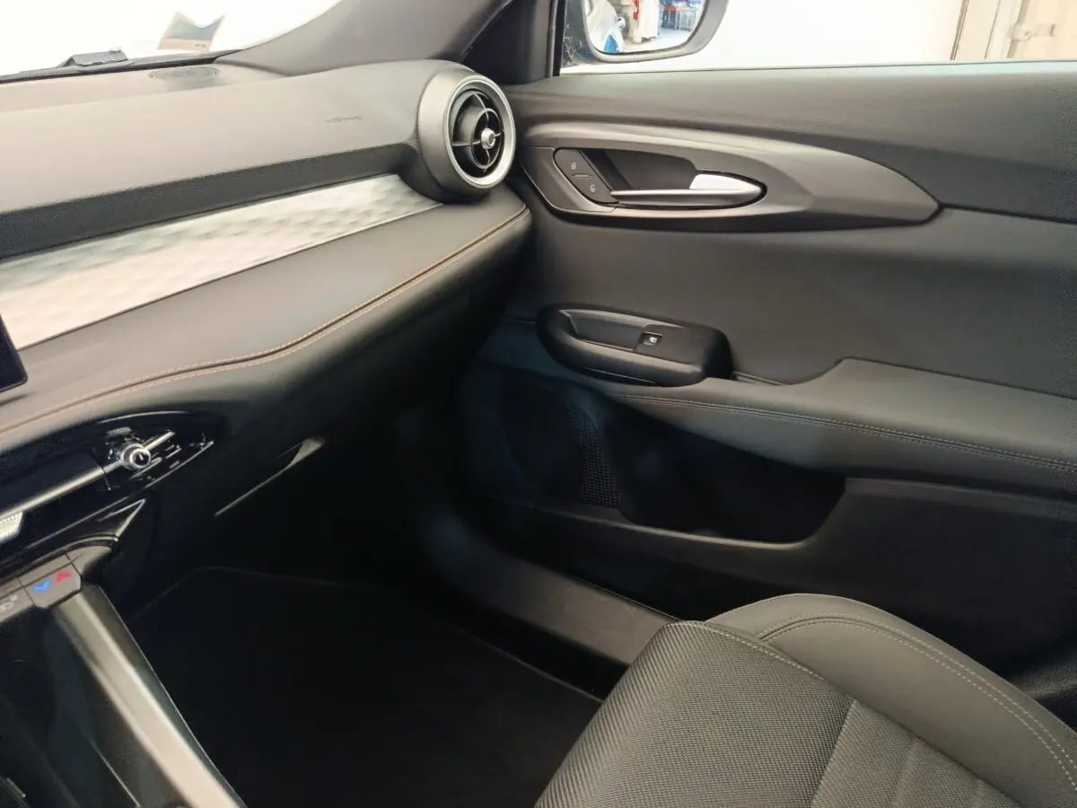 Vue intérieure côté passager de l'Alfa Romeo Tonale 1.5T Hybrid 160 VGT avec tableau de bord noir et surpiqûres marron.