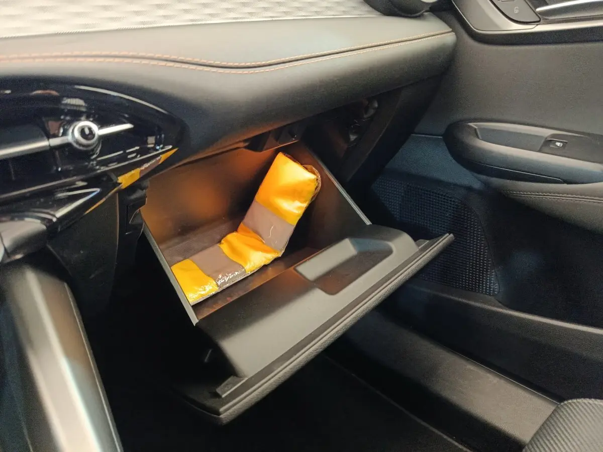 Vue intérieure côté passager de la boîte à gants ouverte de l'Alfa Romeo Tonale 1.5T Hybrid 160 VGT avec gilet de sécurité jaune.