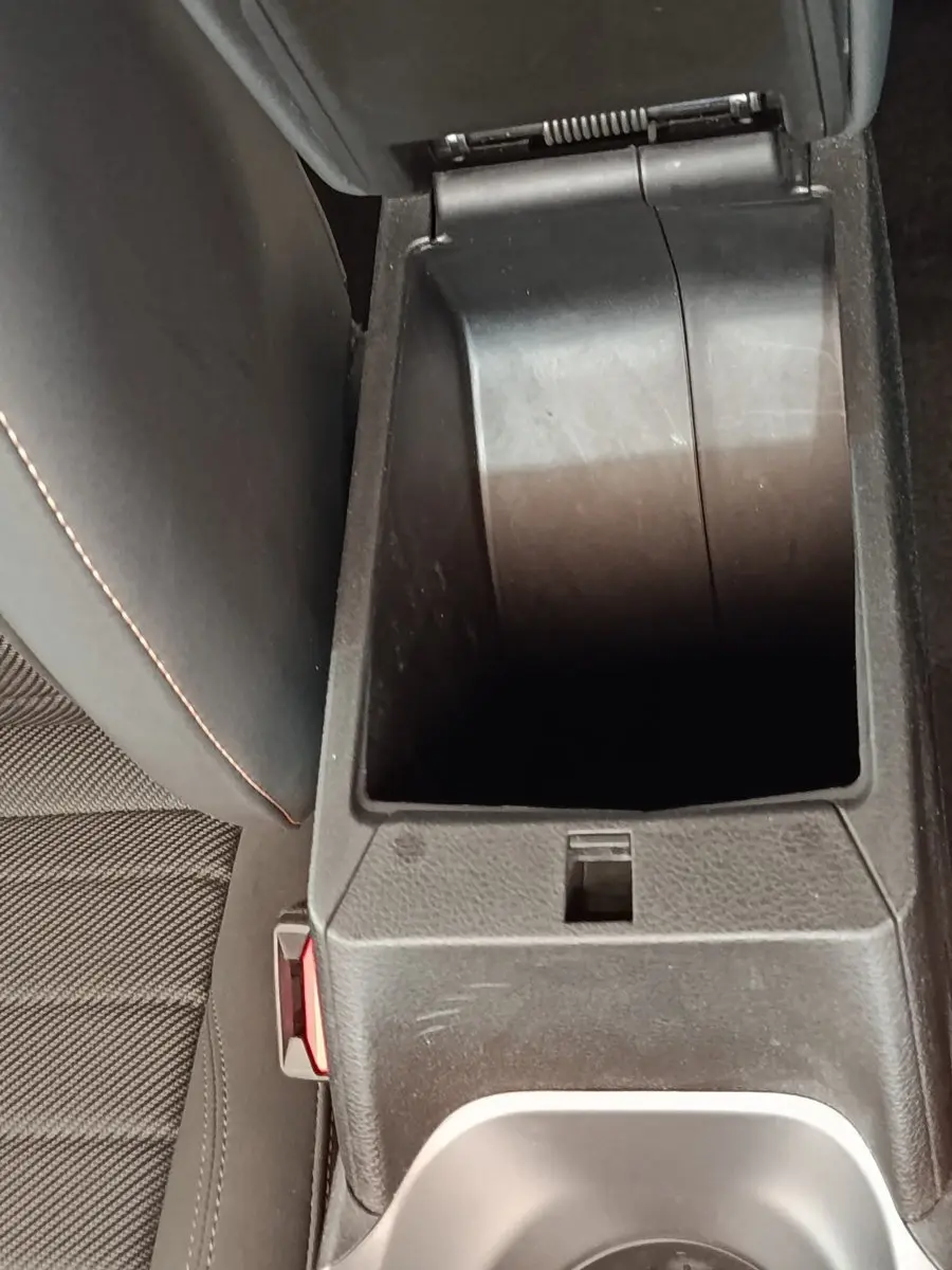 Vue rapprochée de la console centrale ouverte de l'Alfa Romeo Tonale bleu, montrant le rangement intérieur et la sellerie noire.