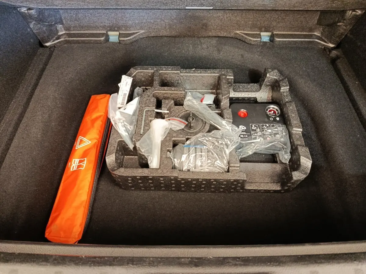 Coffre ouvert d'une Alfa Romeo Tonale bleu, montrant le rangement d'accessoires et la trousse de sécurité orange.