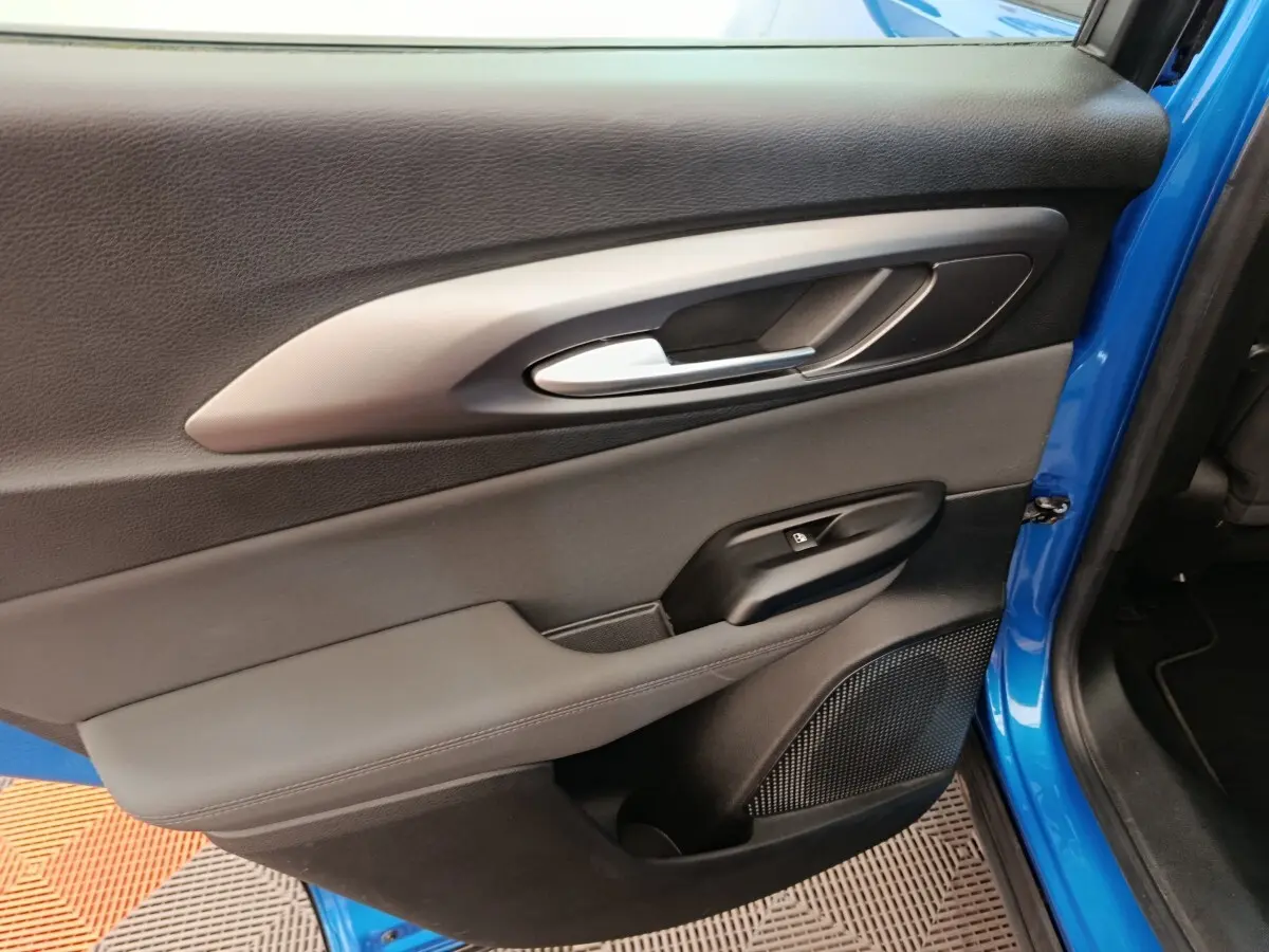 Vue rapprochée de la porte arrière gauche bleu vif de l'Alfa Romeo Tonale 2023 avec poignée argentée et commande de fenêtre.