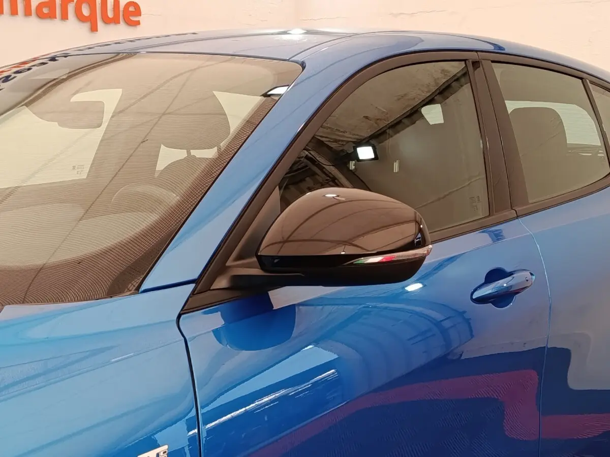 Vue rapprochée côté gauche d’une Alfa Romeo Tonale 1.5T Hybrid 160 VGT bleu avec rétroviseur noir brillant.