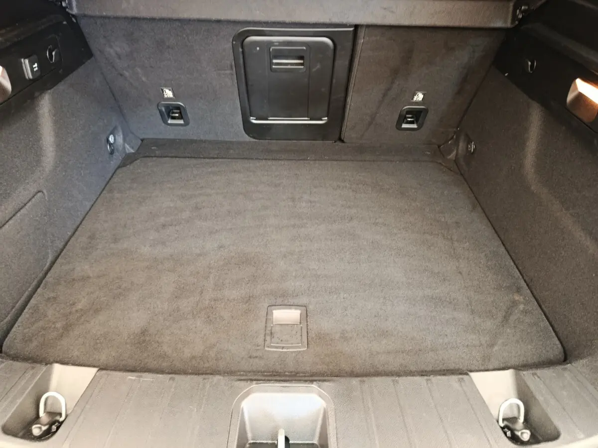 Coffre spacieux de l'Alfa Romeo Tonale 1.5T Hybrid 160 VGT, vue intérieure arrière avec tapis gris foncé.