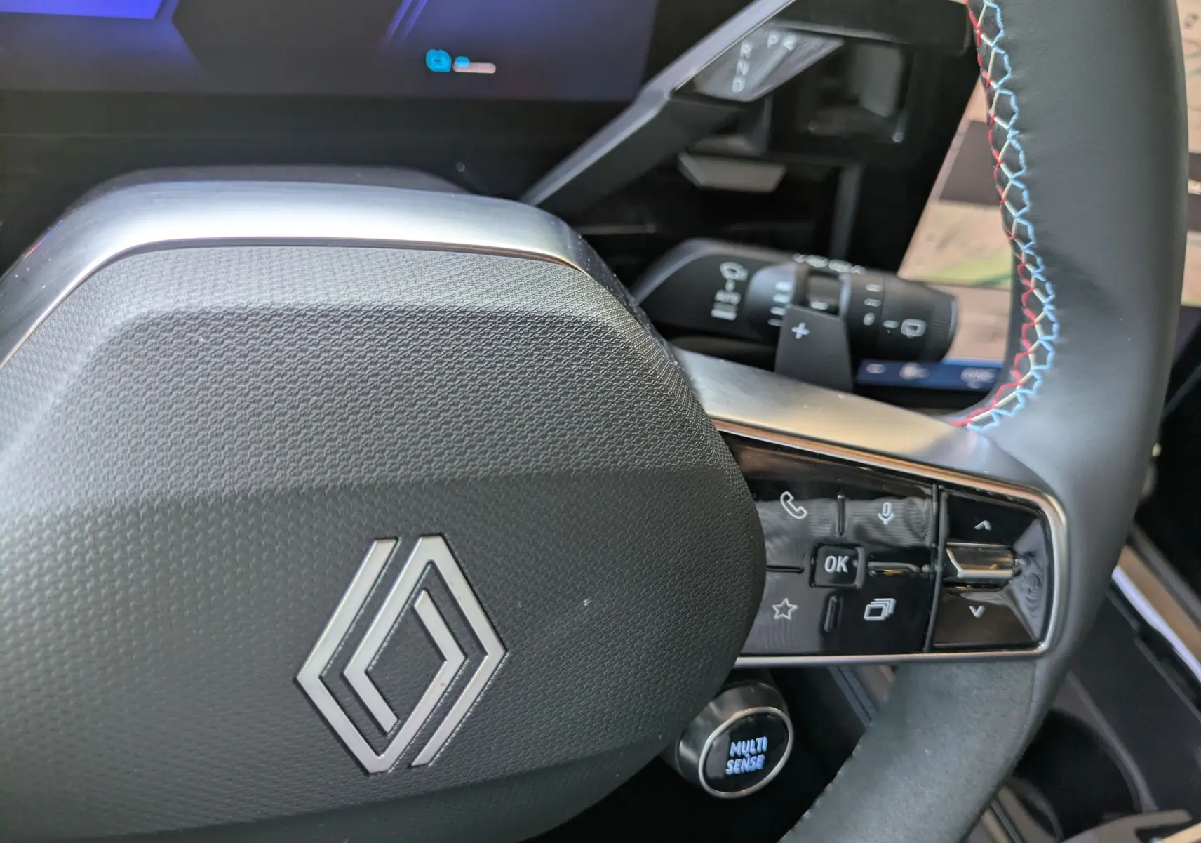 Gros plan sur le volant du Renault Espace VI E-Tech, avec logo Alpine et commandes multifonctions sur cuir noir.