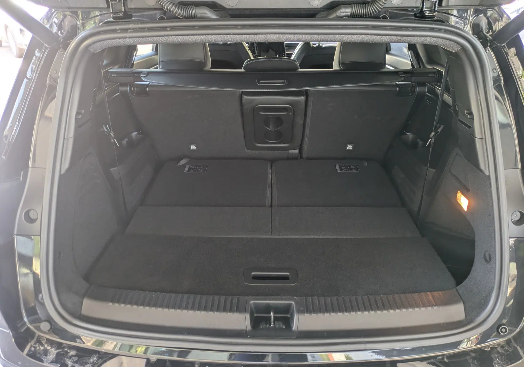Vue arrière du coffre ouvert du Renault Espace VI noir étoile, montrant l'espace de chargement avec sièges rabattus.