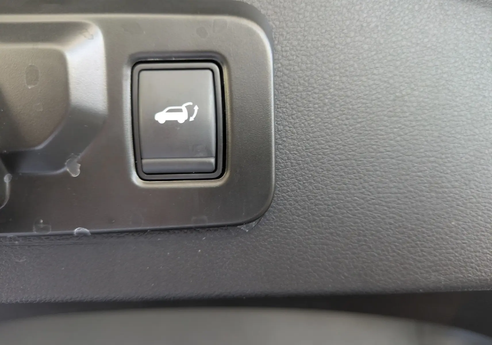 Bouton intérieur noir avec symbole d'ouverture du hayon, sur tableau de bord texturé du Renault Espace VI noir étoile.