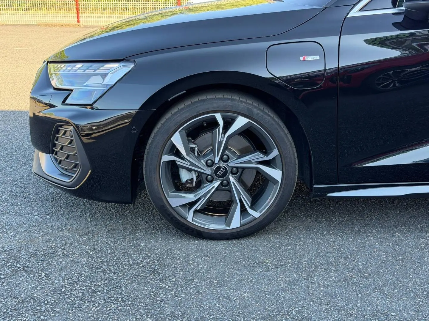 Gros plan sur la roue avant gauche et la partie avant noire métallisée d’une Audi A3 Sportback S line 2025.