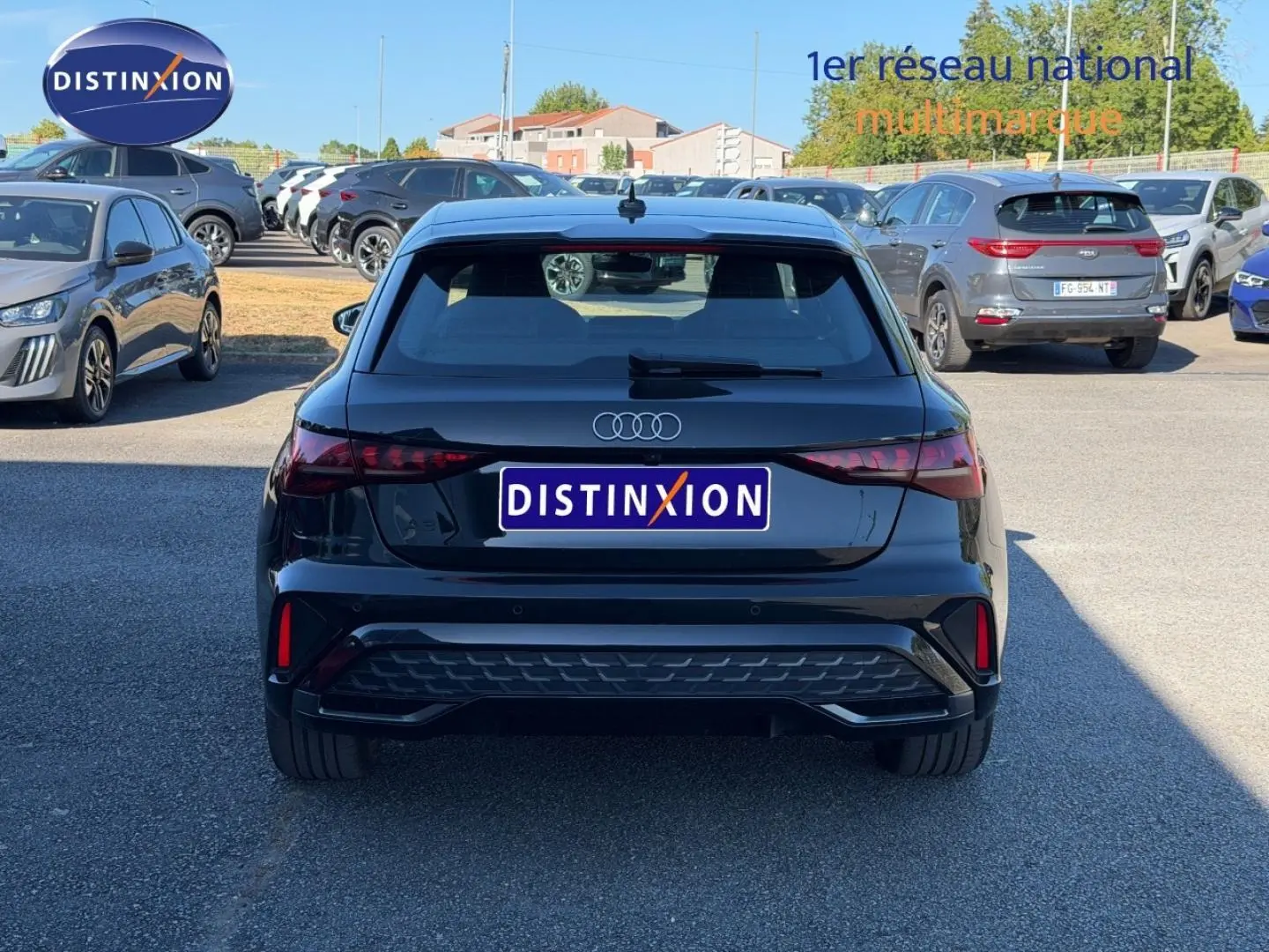 Vue arrière d'une Audi A3 Sportback 2025 noir Mythic métallisé stationnée en extérieur sur parking.