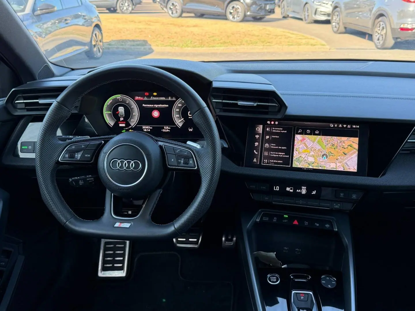Vue intérieure frontale du tableau de bord noir de l'Audi A3 Sportback 2025 avec volant sport et écran multifonction.