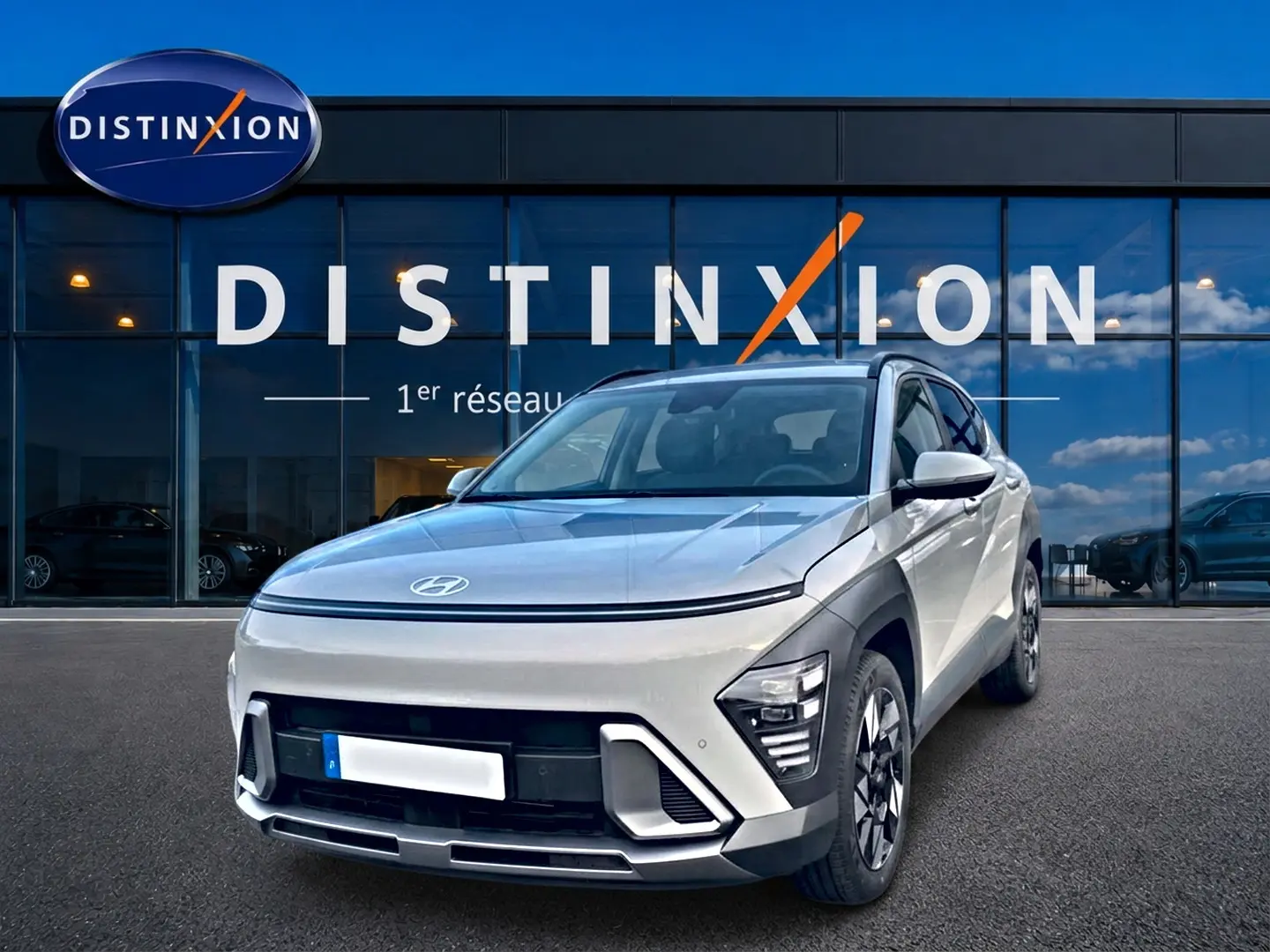 Hyundai Kona gris 2025 en 3/4 avant droit, avec feux LED et jantes alliage devant showroom Distinxion.