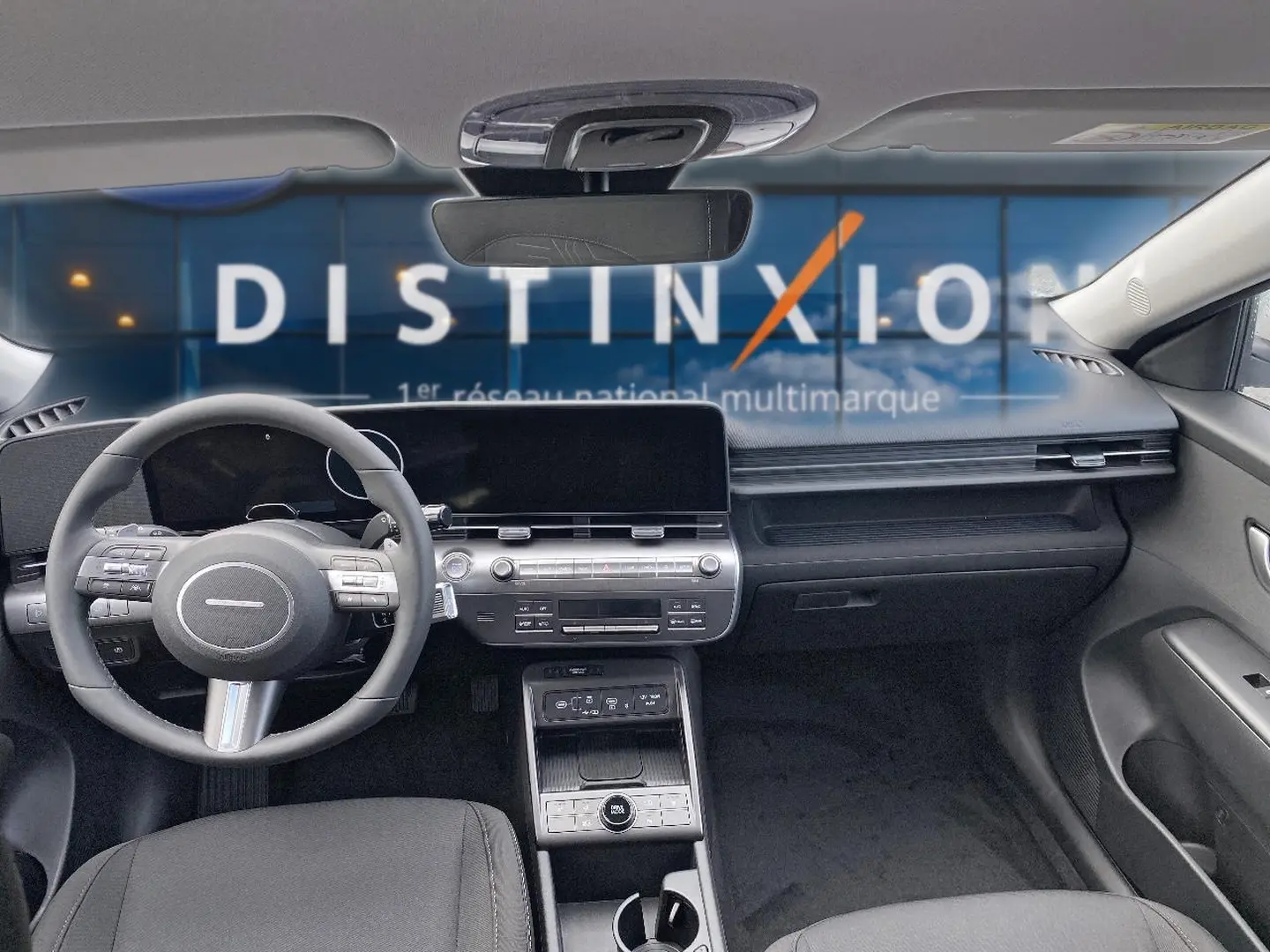 Intérieur avant du Hyundai Kona gris 2025, tableau de bord moderne avec écran large et volant multifonction cuir.