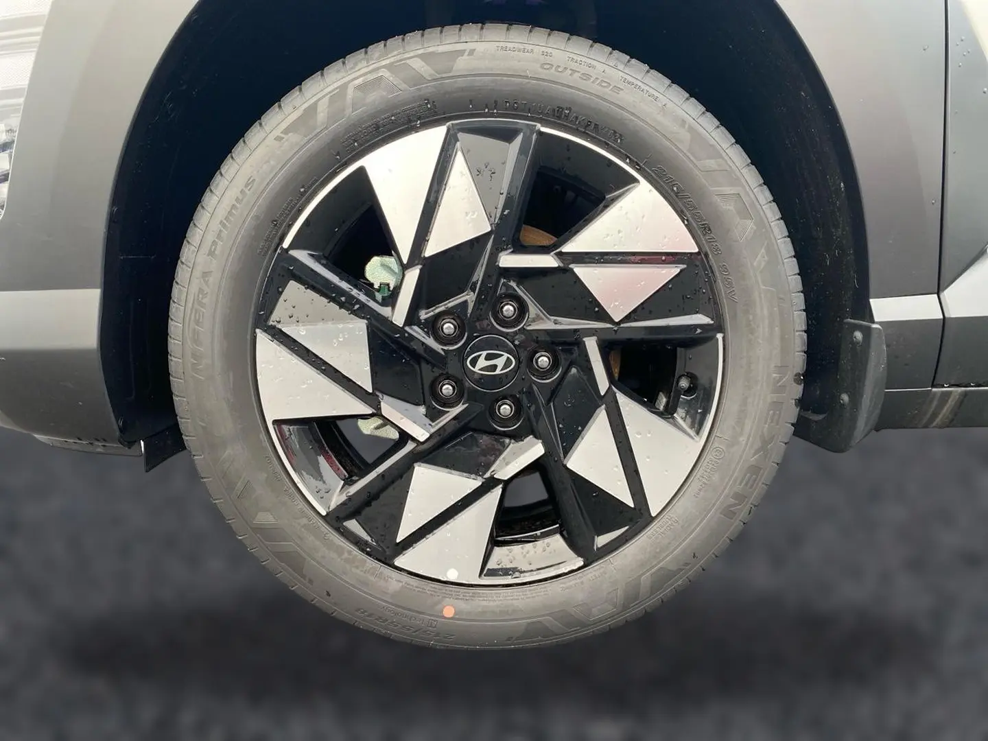 Gros plan sur la roue avant droite du Hyundai Kona gris 2025, jante alliage noire et argentée au design géométrique.